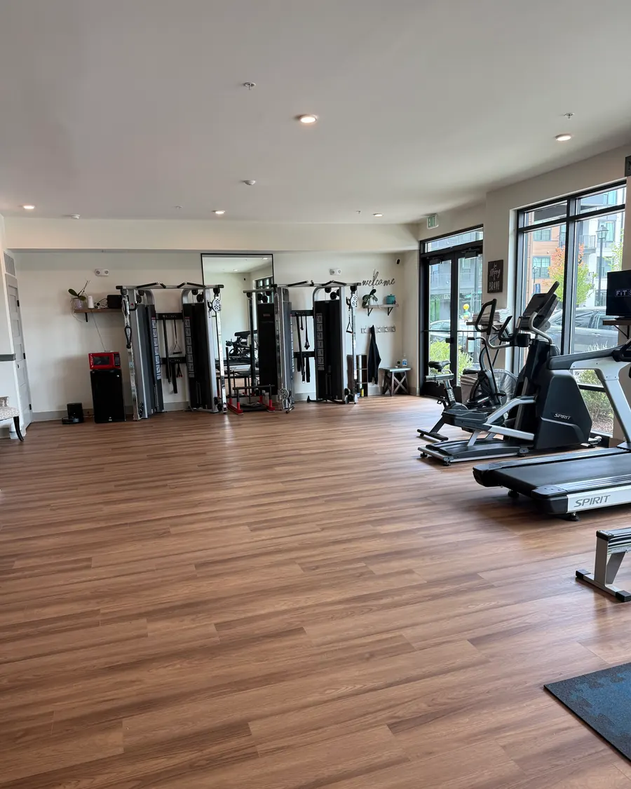 The main floor of Fit Studio: wood floor, white walls, and a wall of windows letting in daylight.