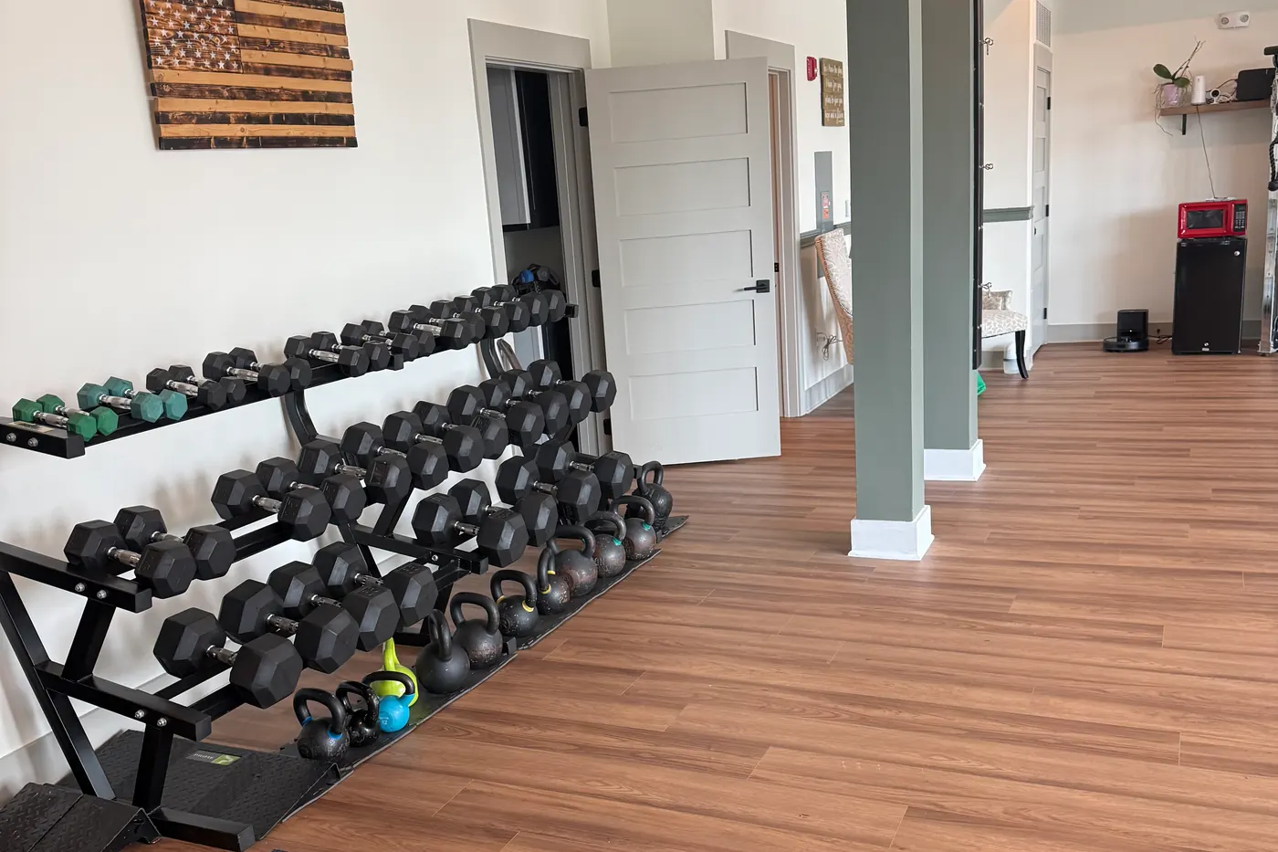 Dumbbell racks and kettlebells along a white wall, with the studio opening up beyond.